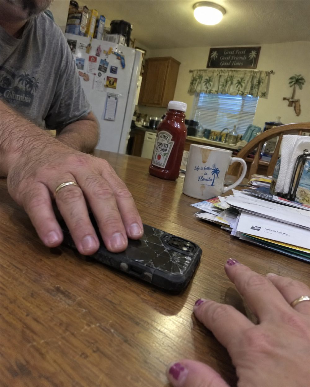 His hand next to his phone on the kitchen table