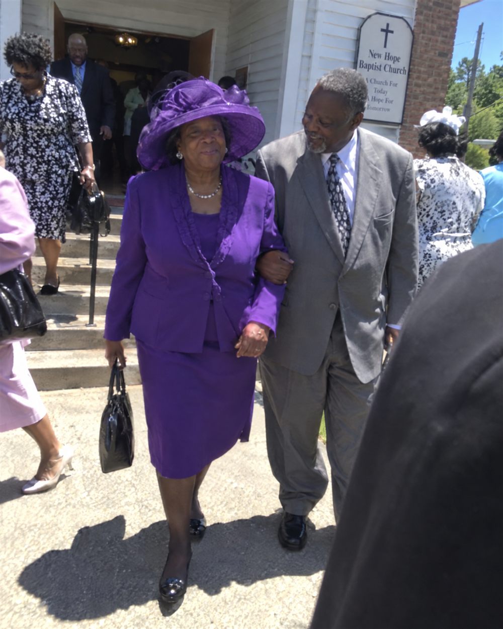 Older couple in church clothes walking arm in arm outside church