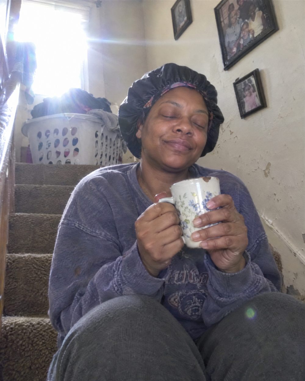 Woman in a bonnet smiling with a mug of coffee on the stairs
